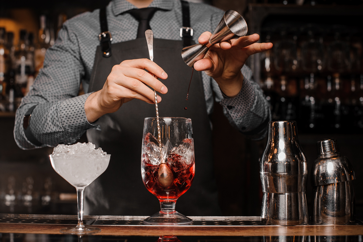 Bartender som gör en alkoholhaltig drink med is i ett cocktailglas Gå ut i Amsterdam/ cocktail shaker